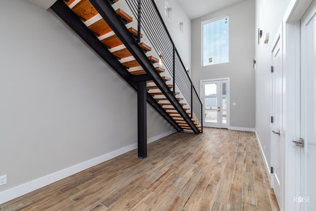 entrance foyer with light hardwood / wood-style flooring, a healthy amount of sunlight, and a high ceiling