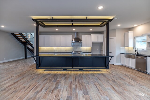 kitchen with a large island, white cabinetry, dishwasher, and wall chimney exhaust hood