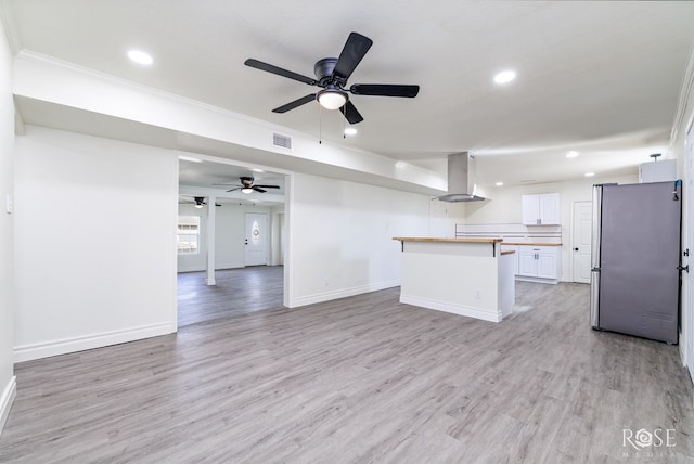 4815 Bowie St, San Angelo, TX 76903 - kitchen with freestanding refrigerator, island exhaust hood, open floor plan, white cabinetry, and ceiling fan