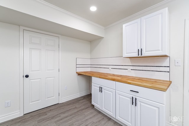 4815 Bowie St, San Angelo, TX 76903 - kitchen with wood counters, crown molding, white cabinets, decorative backsplash, and light wood-style flooring