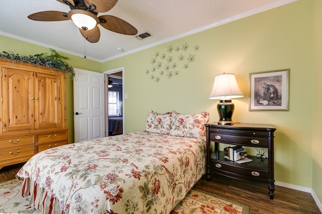 bedroom featuring visible vents, crown molding, baseboards, wood finished floors, and a ceiling fan