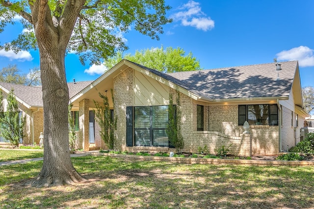 mid-century inspired home with brick siding and a shingled roof