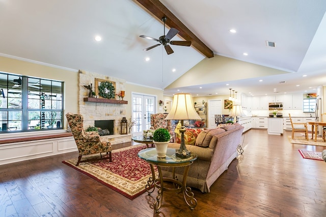 living room featuring beam ceiling, a fireplace, visible vents, ceiling fan, and dark wood-style flooring