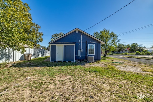 rear view of house with cooling unit, a yard, and an outbuilding