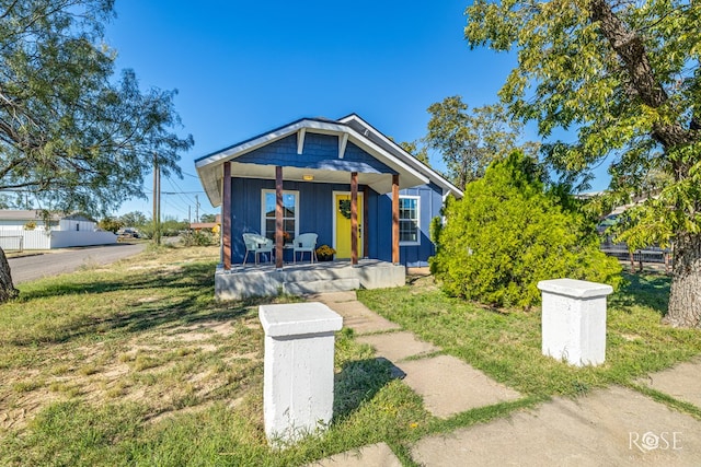 bungalow-style house featuring covered porch and a front lawn