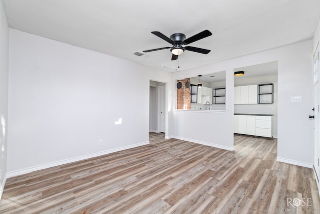 unfurnished living room featuring ceiling fan, sink, and light hardwood / wood-style flooring