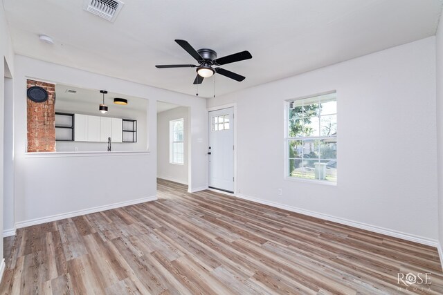 unfurnished living room with plenty of natural light, ceiling fan, and light hardwood / wood-style flooring