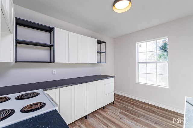 kitchen with electric range oven, white cabinets, and light wood-type flooring