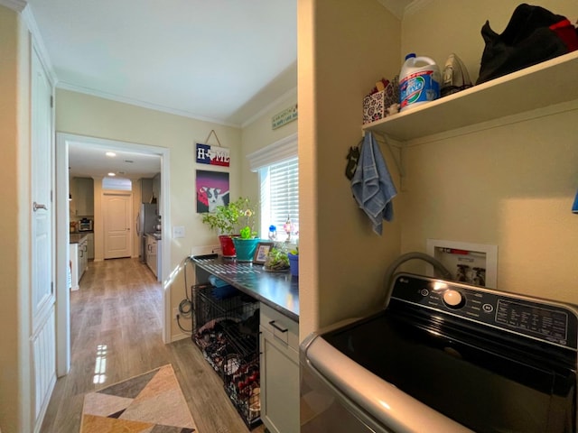 clothes washing area featuring hookup for a washing machine, light wood-type flooring, cabinet space, and crown molding