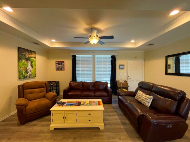 living room with recessed lighting, a raised ceiling, crown molding, and wood finished floors