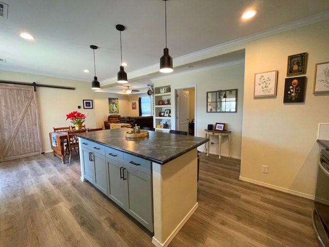 kitchen featuring dark countertops, dark wood-style flooring, a kitchen island, and a barn door