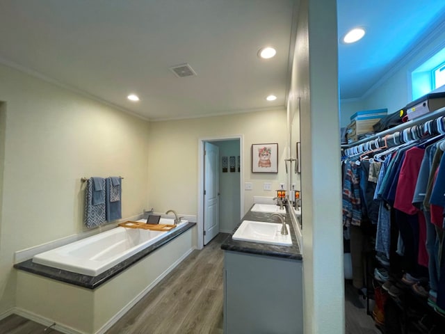 bathroom with crown molding, double vanity, visible vents, a spacious closet, and wood finished floors