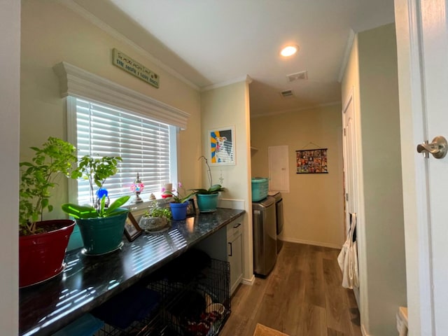 interior space with visible vents, washer and clothes dryer, baseboards, ornamental molding, and light wood-style floors