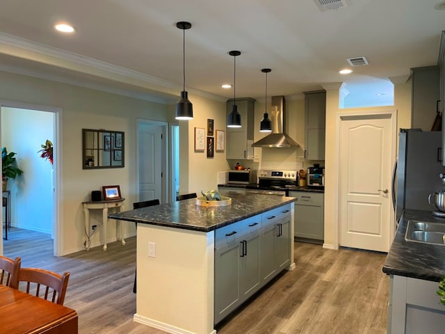 kitchen featuring stainless steel appliances, light wood-type flooring, wall chimney range hood, and gray cabinetry