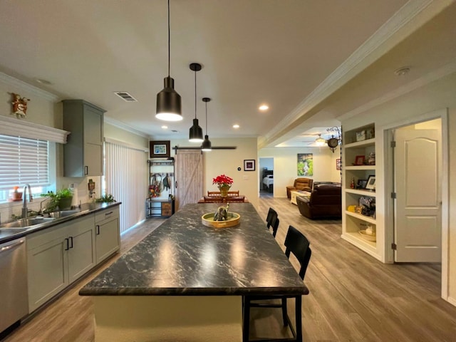 kitchen with a barn door, a sink, visible vents, stainless steel dishwasher, and dark countertops