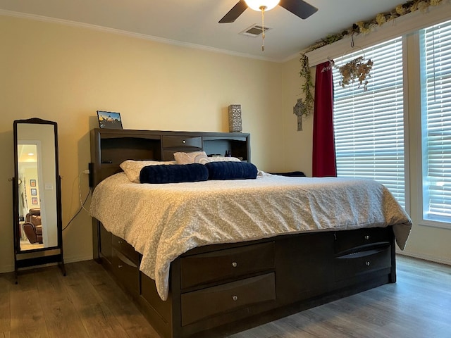 bedroom featuring visible vents, crown molding, baseboards, and wood finished floors