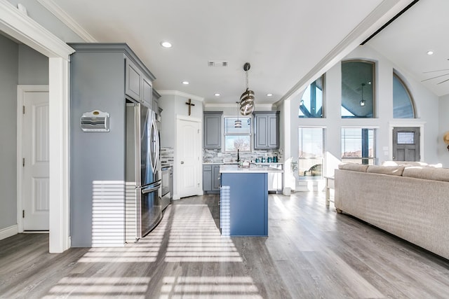 kitchen featuring gray cabinets, appliances with stainless steel finishes, backsplash, hanging light fixtures, and a center island