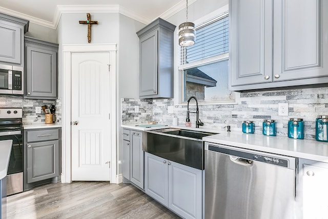 kitchen featuring pendant lighting, sink, ornamental molding, and stainless steel appliances