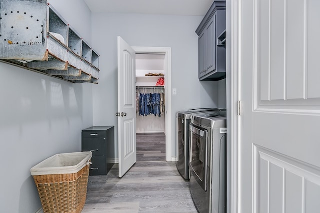 clothes washing area featuring light hardwood / wood-style floors, cabinets, and washing machine and clothes dryer