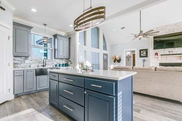 kitchen featuring a kitchen island, tasteful backsplash, sink, ornamental molding, and light hardwood / wood-style floors