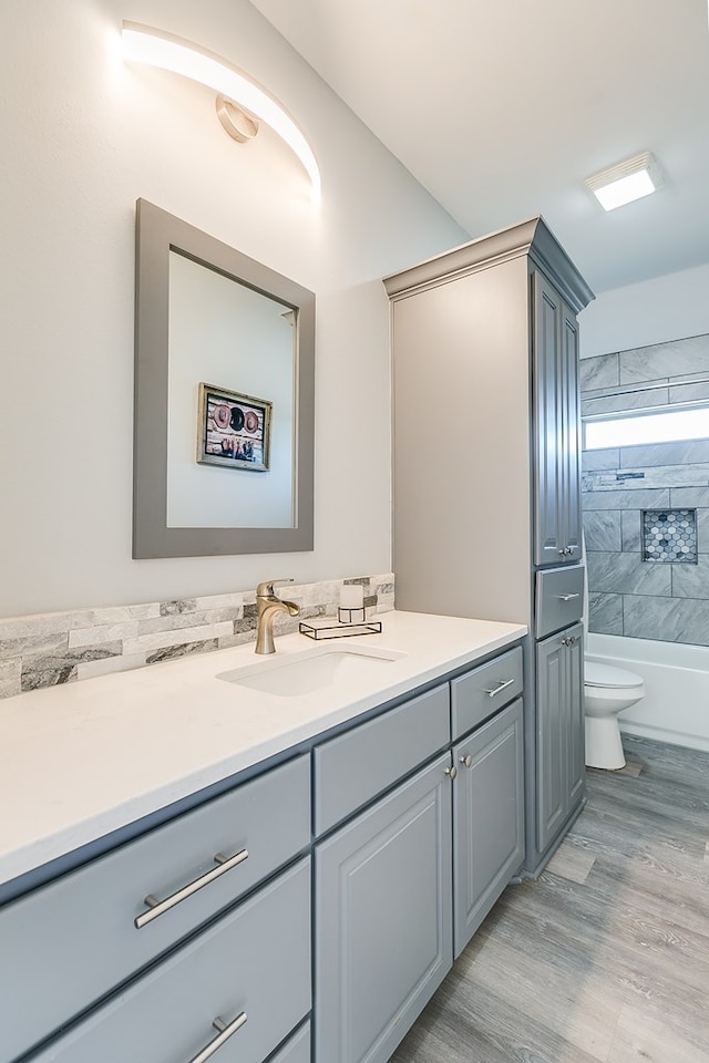 full bathroom featuring vanity, tiled shower / bath, wood-type flooring, and toilet