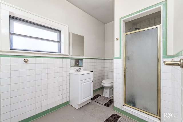 bathroom with vanity, toilet, a shower with shower door, and tile walls