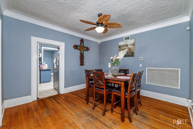 dining space with hardwood / wood-style floors, a textured ceiling, ornamental molding, and ceiling fan