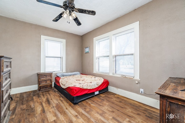 bedroom with dark hardwood / wood-style floors, a textured ceiling, and ceiling fan