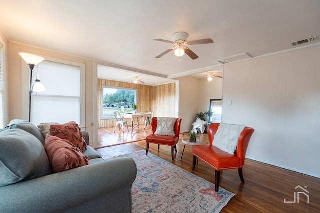 living room featuring dark wood-type flooring, ornamental molding, and ceiling fan