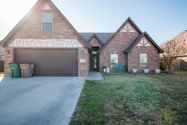 tudor-style house featuring a garage, concrete driveway, brick siding, and a front lawn