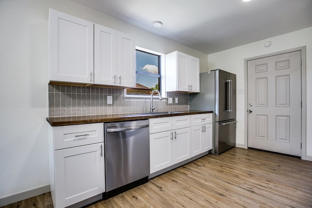 1106 Gregory Dr, San Angelo, TX 76905 - kitchen featuring appliances with stainless steel finishes, dark countertops, backsplash, light wood-style floors, and white cabinetry