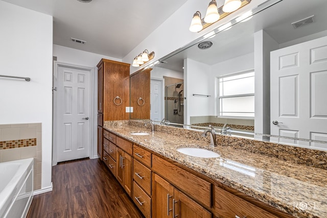 4129 Sedona Trl, San Angelo, TX 76904 - bathroom featuring a bath, double vanity, wood finished floors, and a shower stall