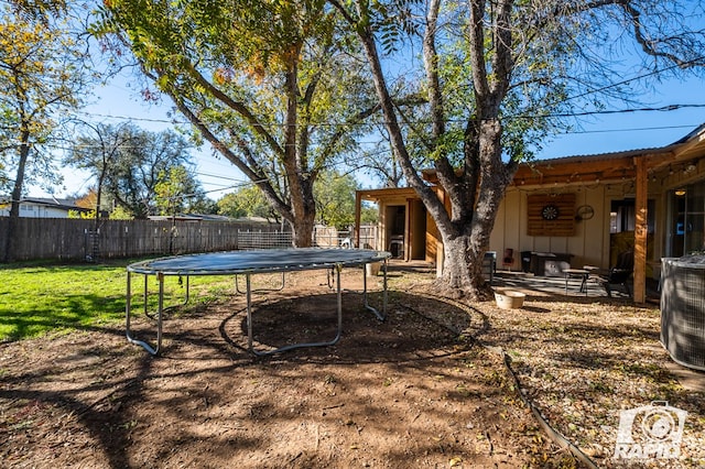 view of yard with central AC unit and a trampoline