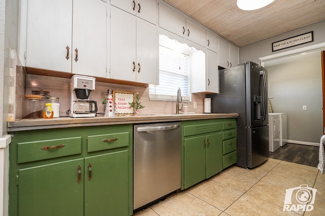 kitchen with white cabinetry, stainless steel appliances, washer and dryer, and light tile patterned floors