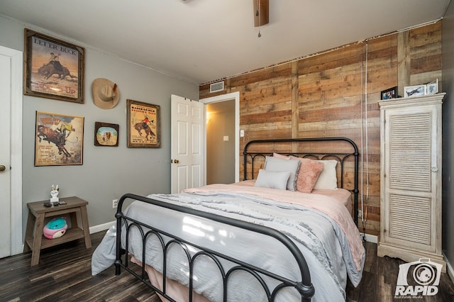 bedroom with dark wood-type flooring and wood walls