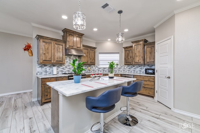 kitchen featuring a kitchen island, a kitchen bar, ornamental molding, light stone counters, and light hardwood / wood-style flooring