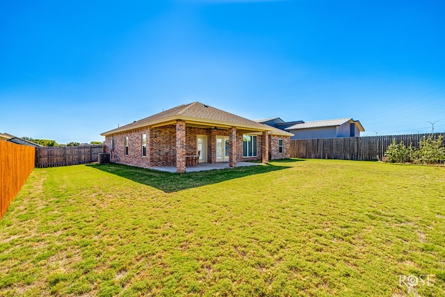 back of house with central AC unit, a lawn, and a patio