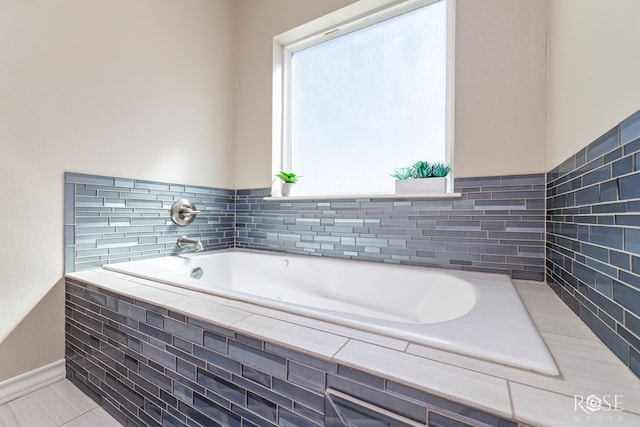 bathroom with tile patterned flooring and tiled bath