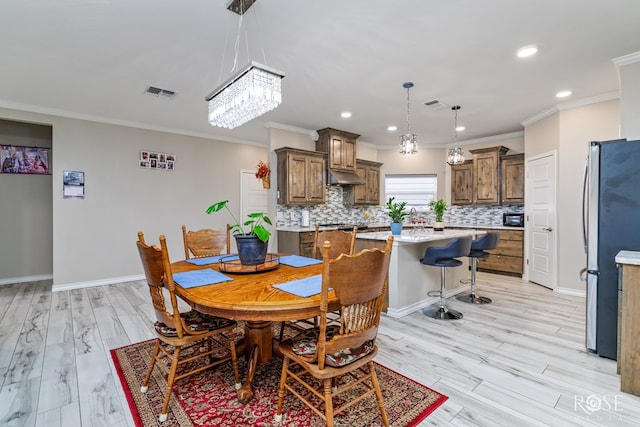 dining space featuring crown molding and light hardwood / wood-style floors