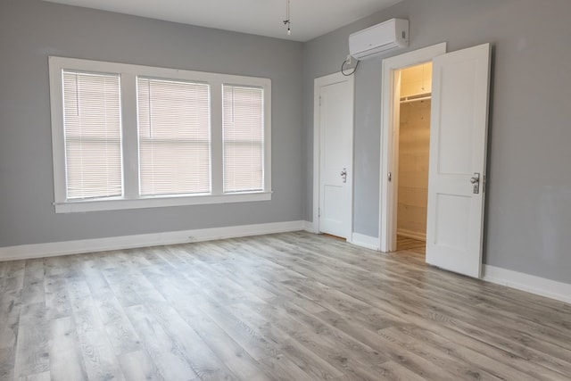 1905 Live Oak St, San Angelo, TX 76901 - unfurnished bedroom featuring baseboards, light wood-style flooring, and an AC wall unit