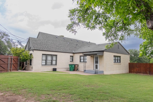 1905 Live Oak St, San Angelo, TX 76901 - rear view of house featuring a yard, a shingled roof, a fenced backyard, brick siding, and a patio area
