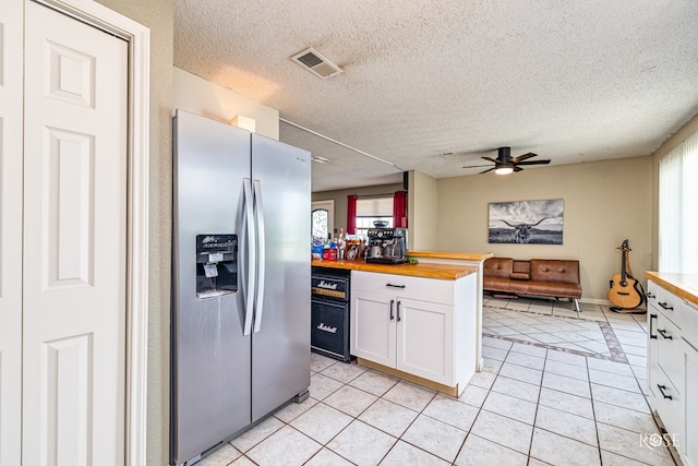 705 Fay St, Sonora, TX 76950 - kitchen with stainless steel fridge, butcher block countertops, white cabinets, light tile patterned floors, and plenty of natural light