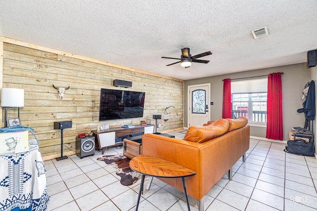 705 Fay St, Sonora, TX 76950 - living room with light tile patterned floors, wooden walls, ceiling fan, and a textured ceiling