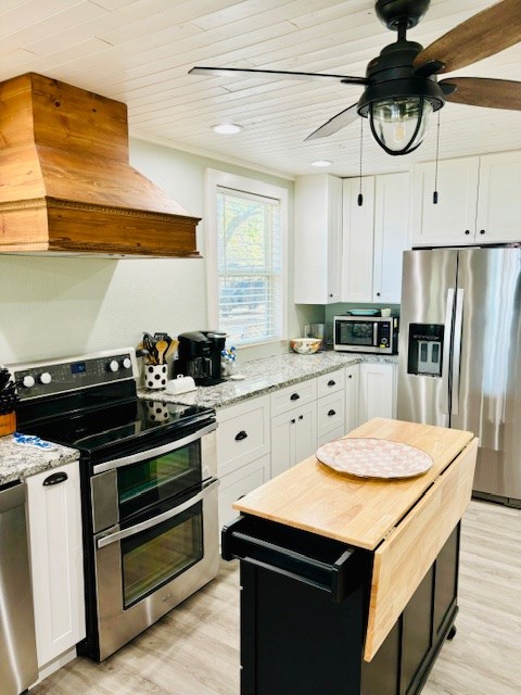 kitchen with premium range hood, light stone counters, stainless steel appliances, light hardwood / wood-style floors, and white cabinets