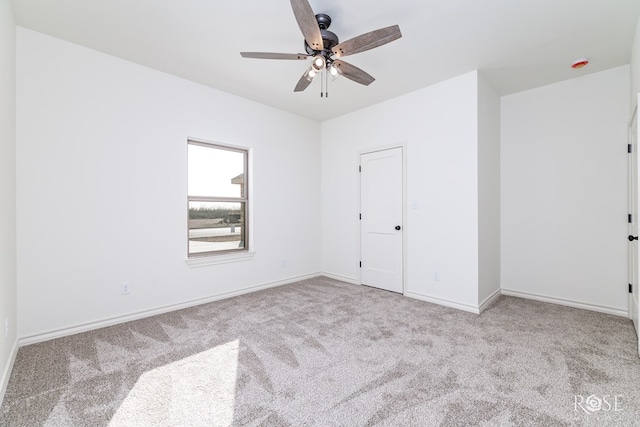 spare room featuring baseboards, a ceiling fan, and light colored carpet