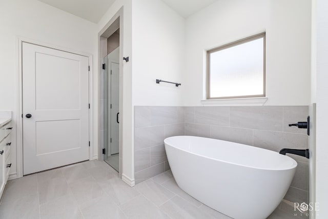 5441 Riviera Ln, San Angelo, TX 76904 - bathroom featuring tile walls, a stall shower, a soaking tub, and vanity
