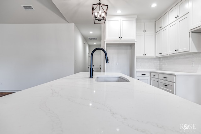 kitchen with visible vents, a sink, decorative light fixtures, and white cabinets