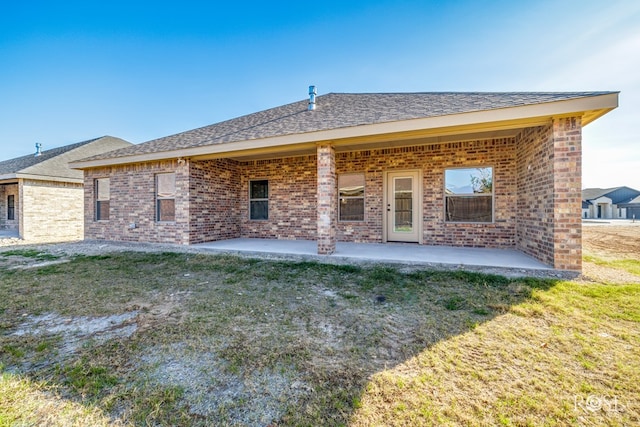 rear view of property with a yard, a patio, and brick siding