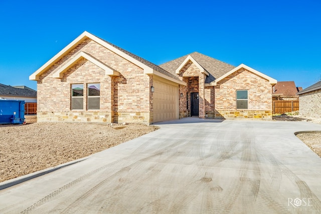 ranch-style home with concrete driveway, brick siding, fence, and an attached garage