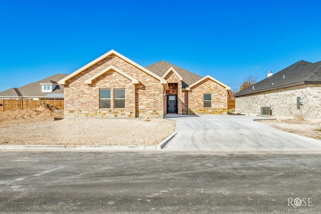 view of front of property with fence, cooling unit, and brick siding